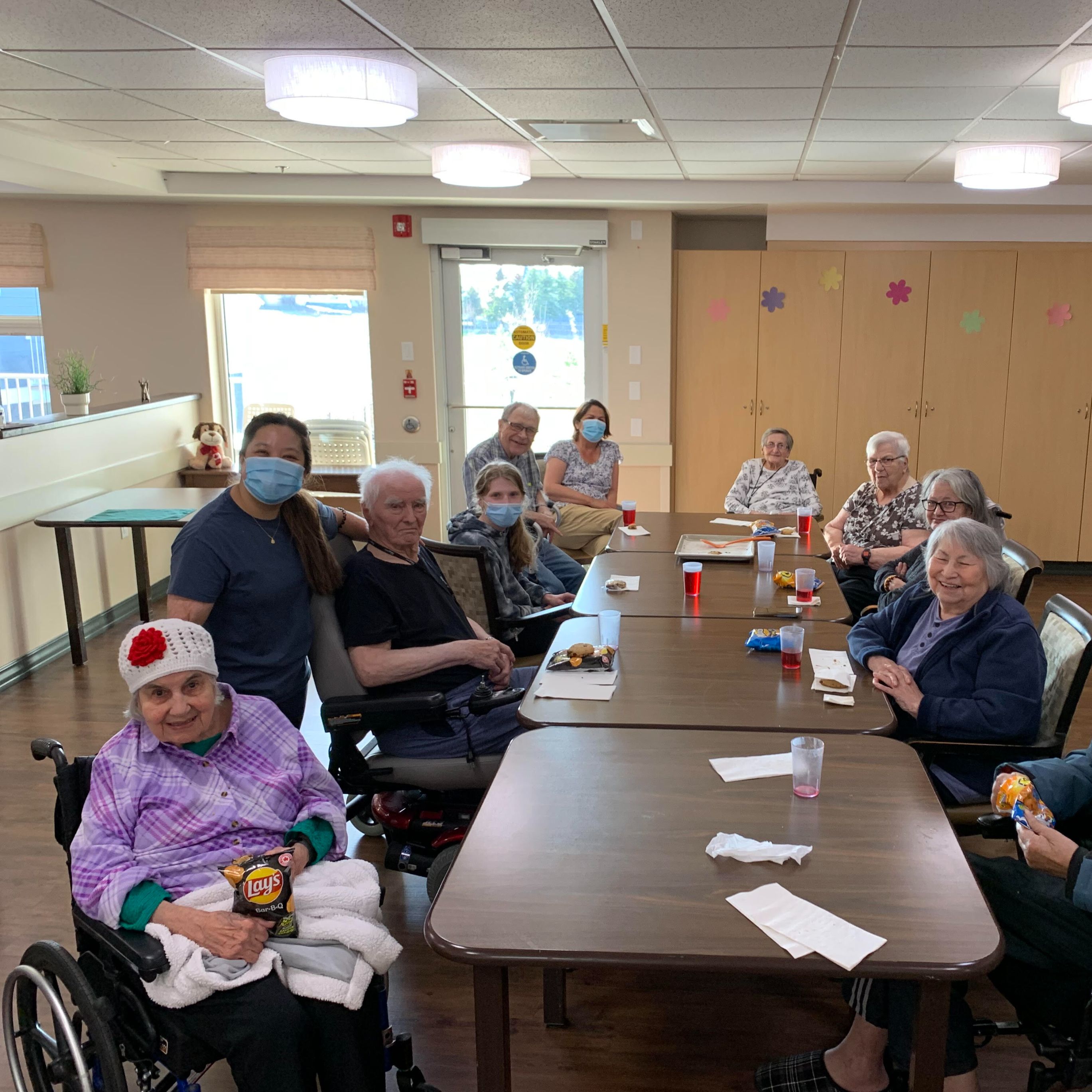 Senior residents seated at a table together with chips and juice.