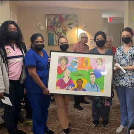 Multiple nurses holding a homemade portrait.