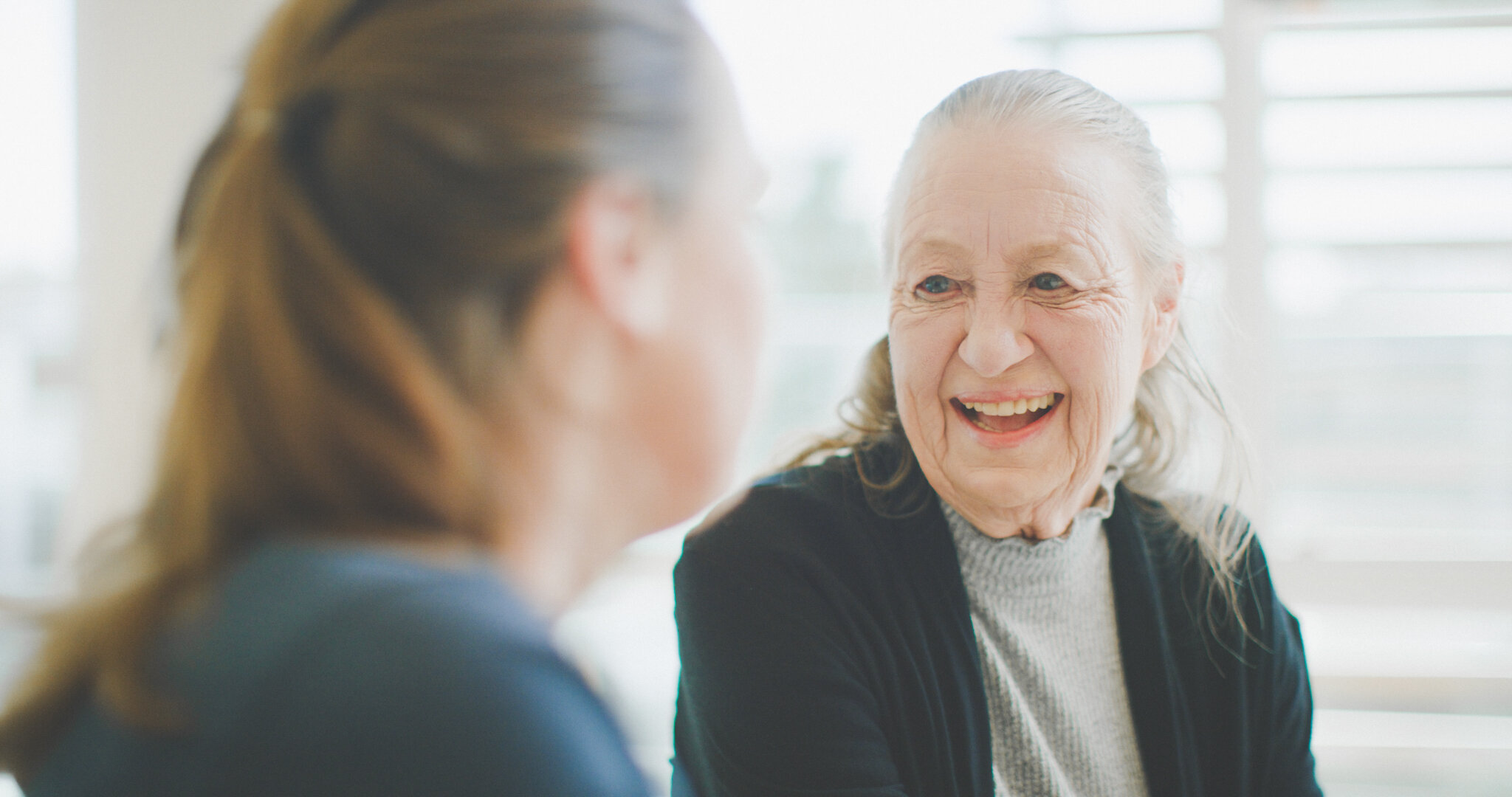 An elderly lady smiling with a young lady