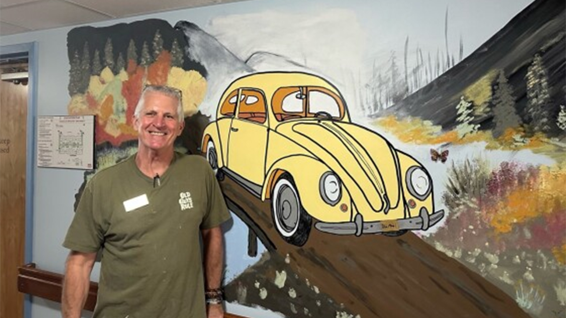 VW beetle mural with man standing in front of it