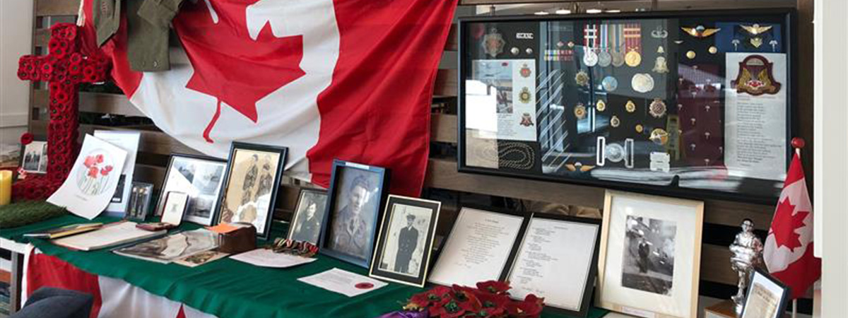 Remembrance Day display featuring a Canadian flag, poppies, photos of relatives, and medallions.