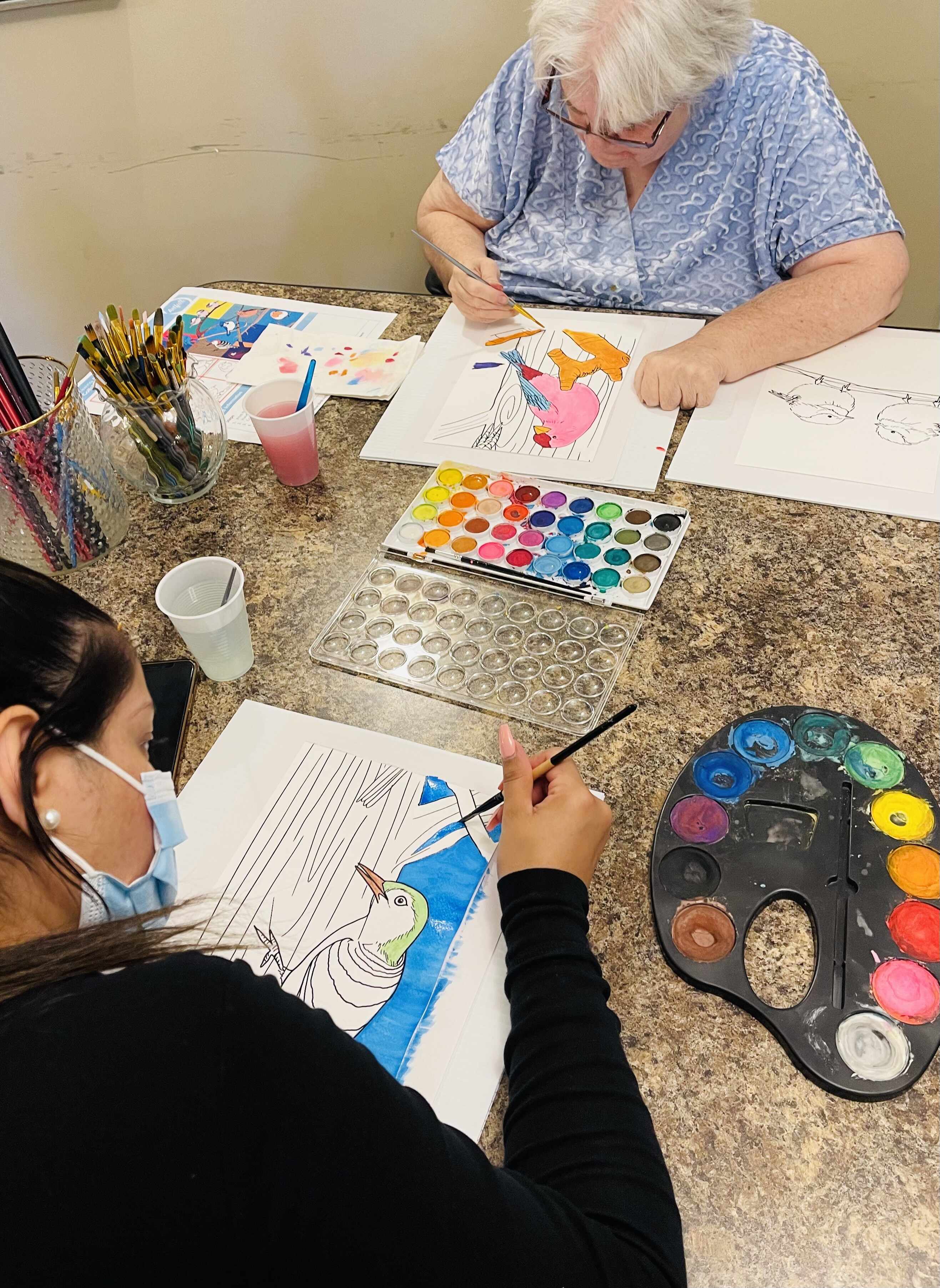 An elderly lady doing painting with a young lady