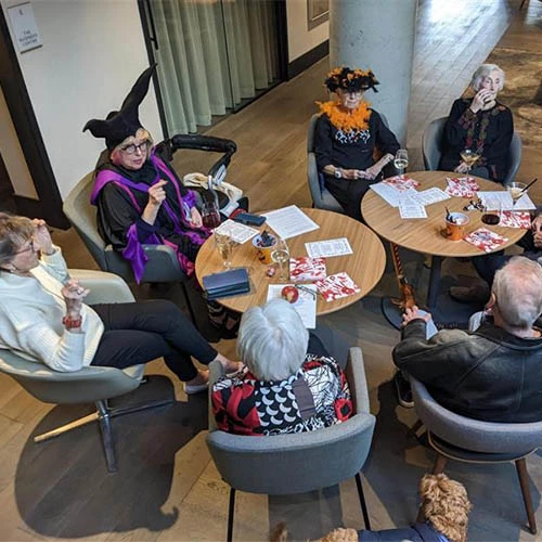 Residents around a table in Halloween costumes spending time together.