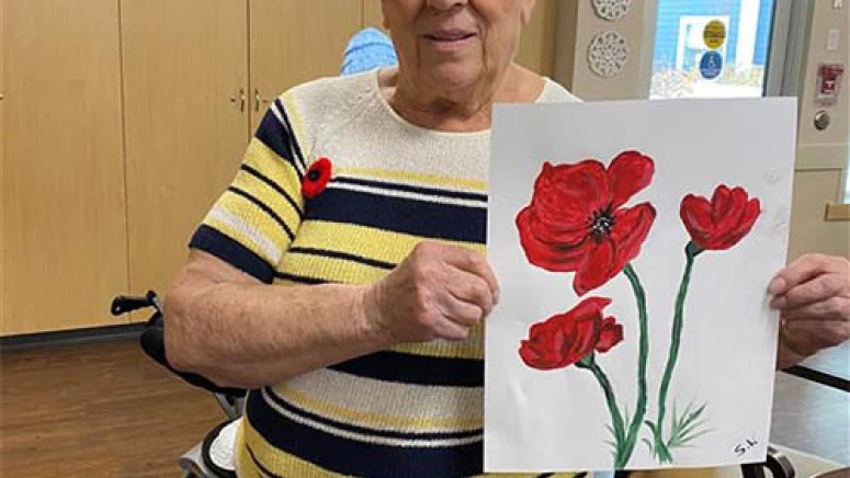 A woman holding a painting of poppies.