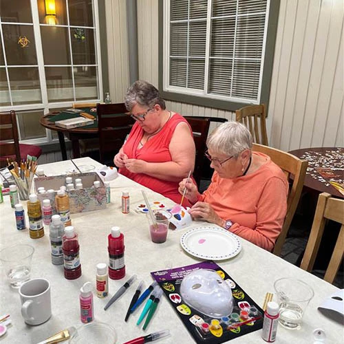 Residents painting masks together with pink, blue, and red paint.