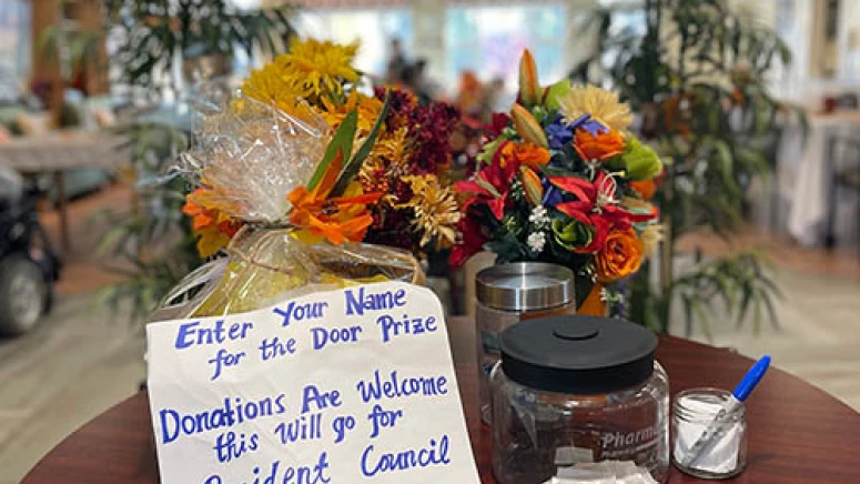 Display for a door prize draw. Flowers are placed behind the sign and jar to enter the draw.