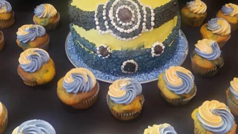 A minions cake with corresponding cupcakes decorated with blue and yellow.