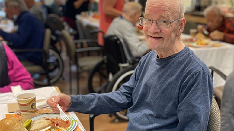 Resident smiling and enjoying a delicious Thanksgiving meal.