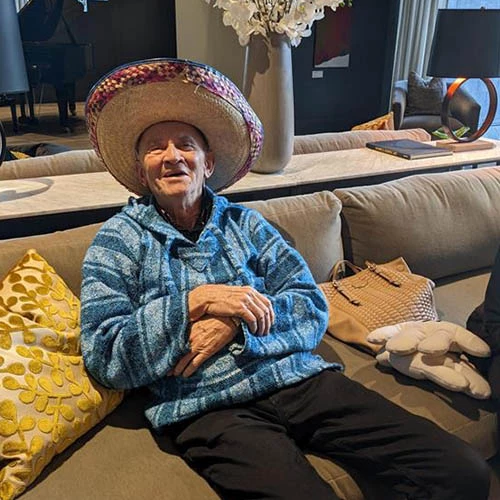 Resident in a sombrero smiling while sitting on a couch.
