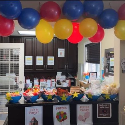 Snacks on a counter with colourful pink, yellow, and blue balloons hung above