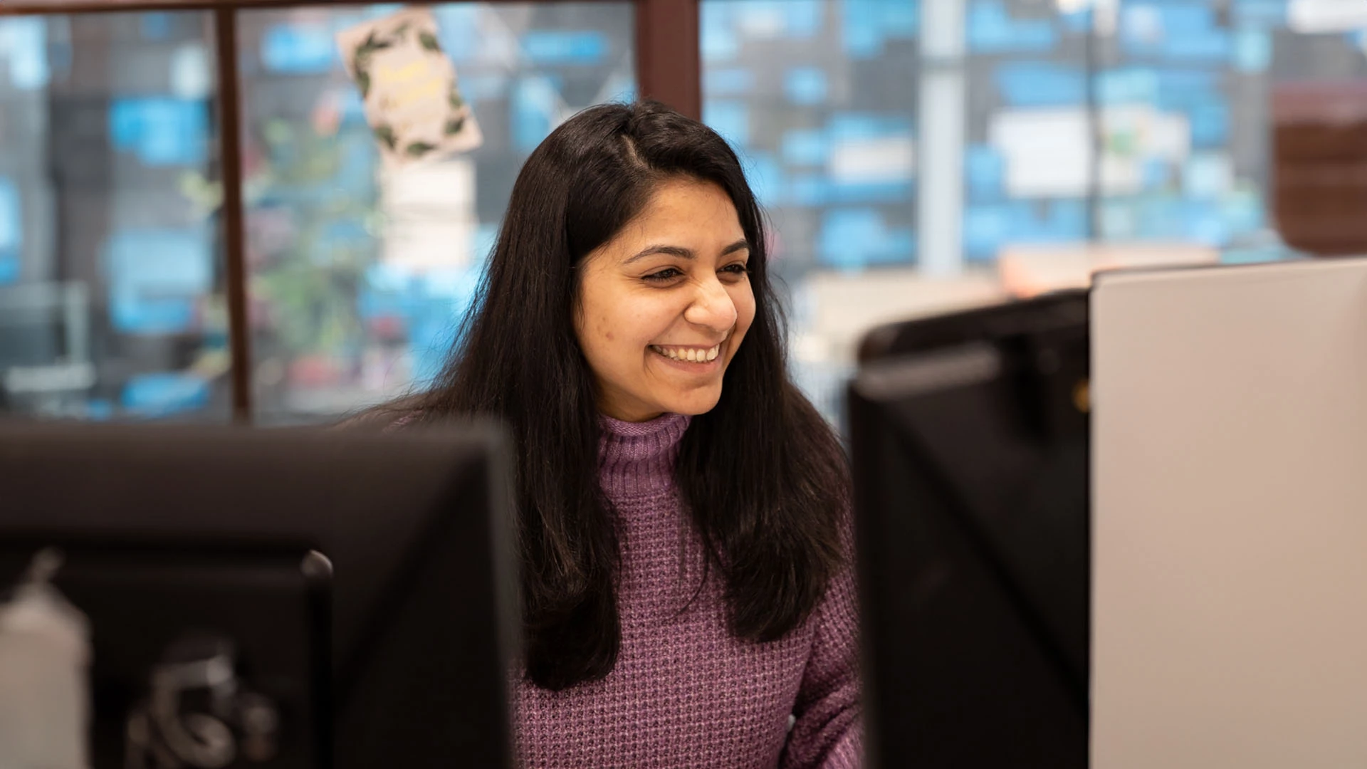 Optima Living staff member smiling while working at her computer desk