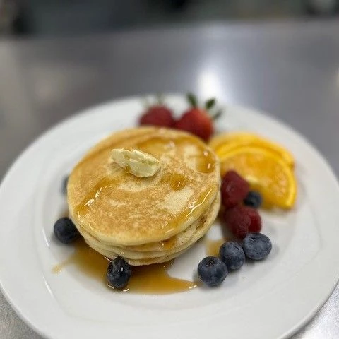 Pancakes on a plate with syrup and fruit