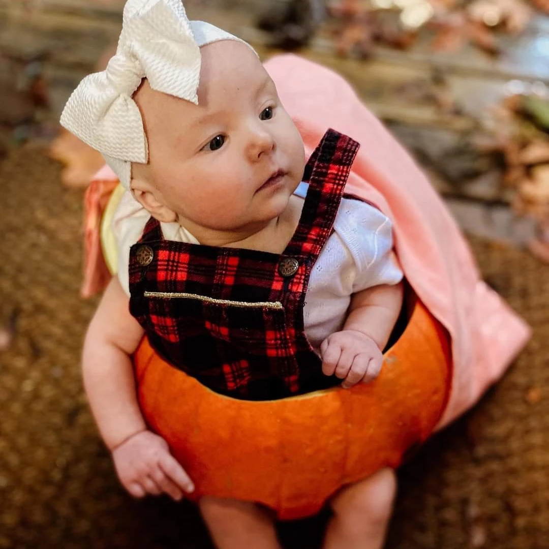 A baby girl in a pumpkin on Halloween party