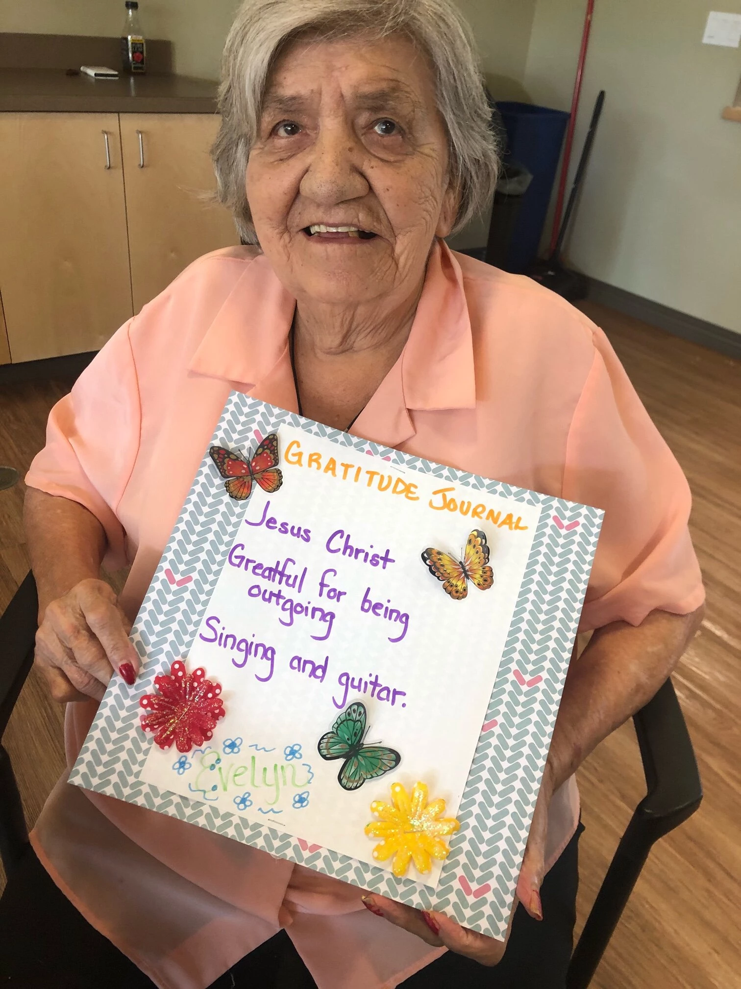 A senior lady holding a gratitude card for singing and guitar