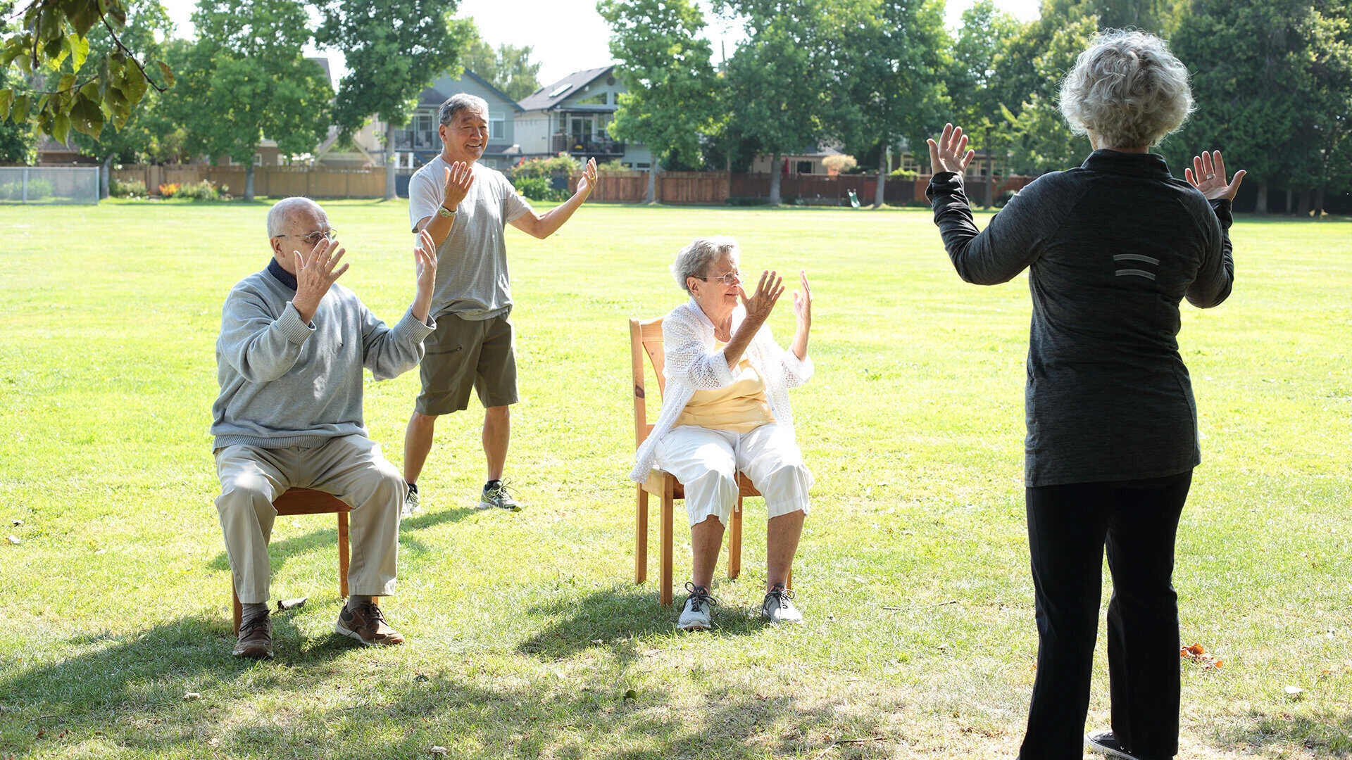 A group of men and women practicing tai chi for seniors in a green field