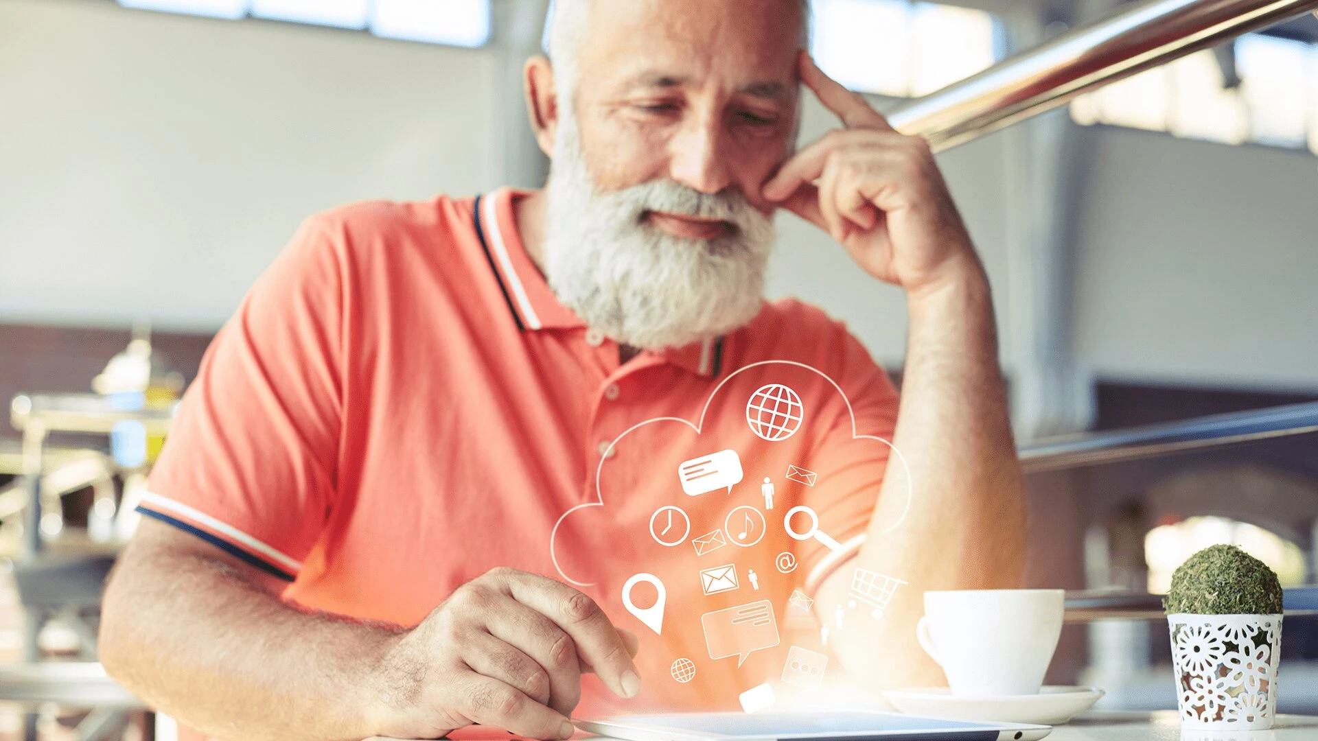 An older man using a tablet while drinking tea in his senior apartment