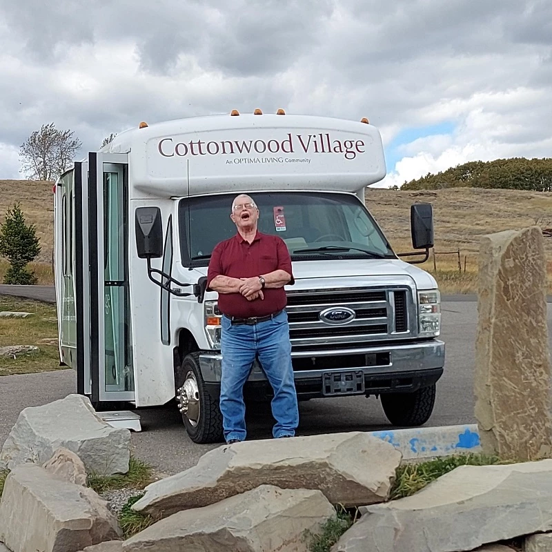 A man standing in front of Shuttle bus of Cottonwood Village