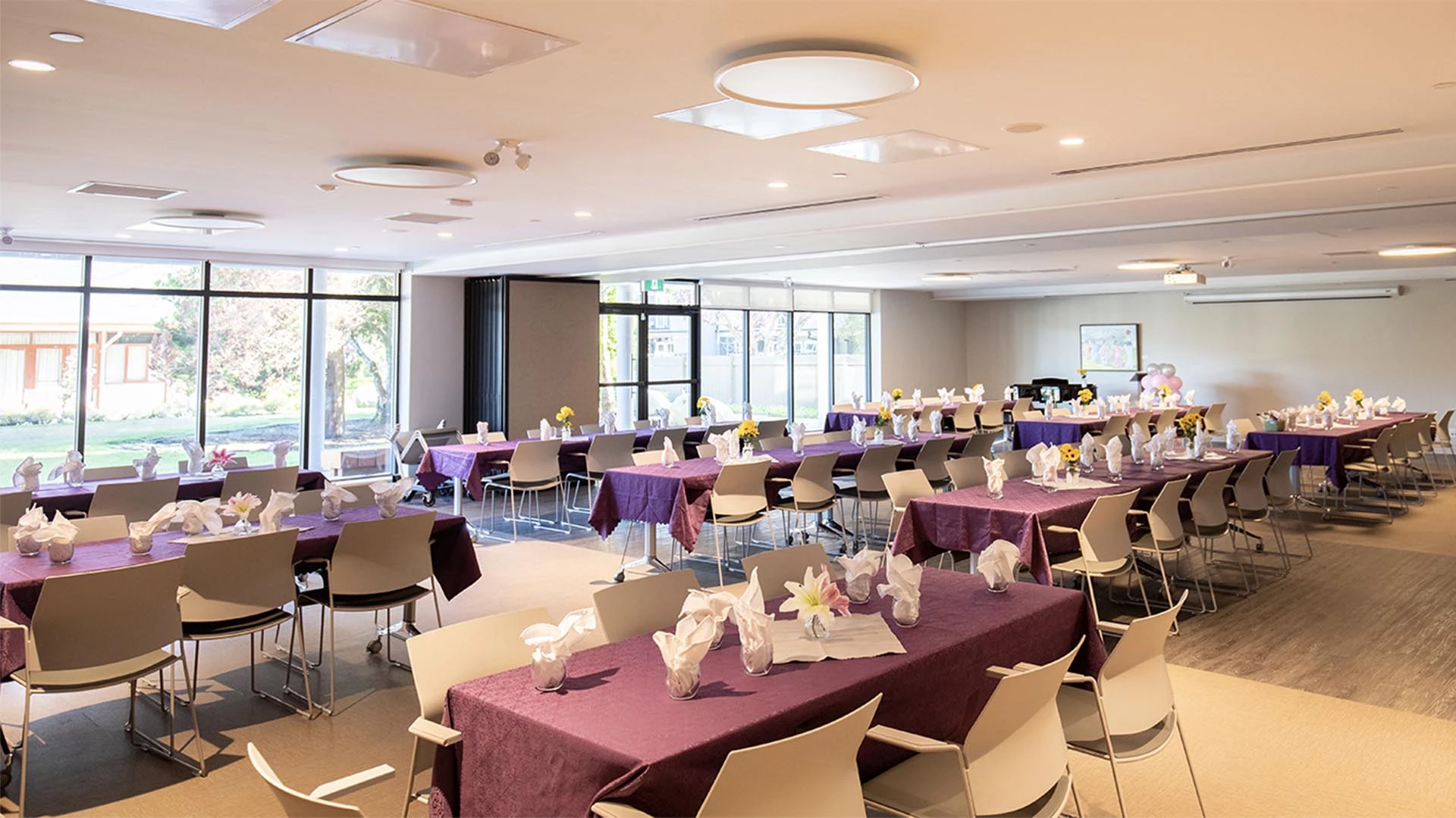 A large dining area with white chairs and purple clothes on tables