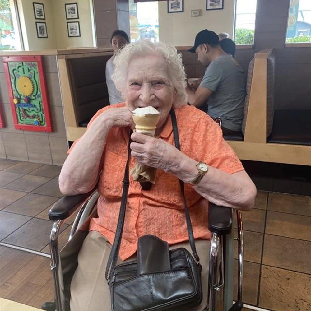 A senior lady in a wheelchair eating an ice cream cone