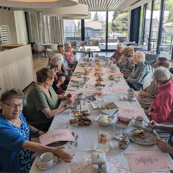 Seniors seated around a table together enjoying tasty treats.