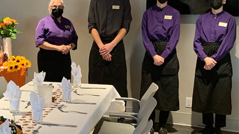 Servers of Wisteria Place standing ready to serve, all are wearing masks.