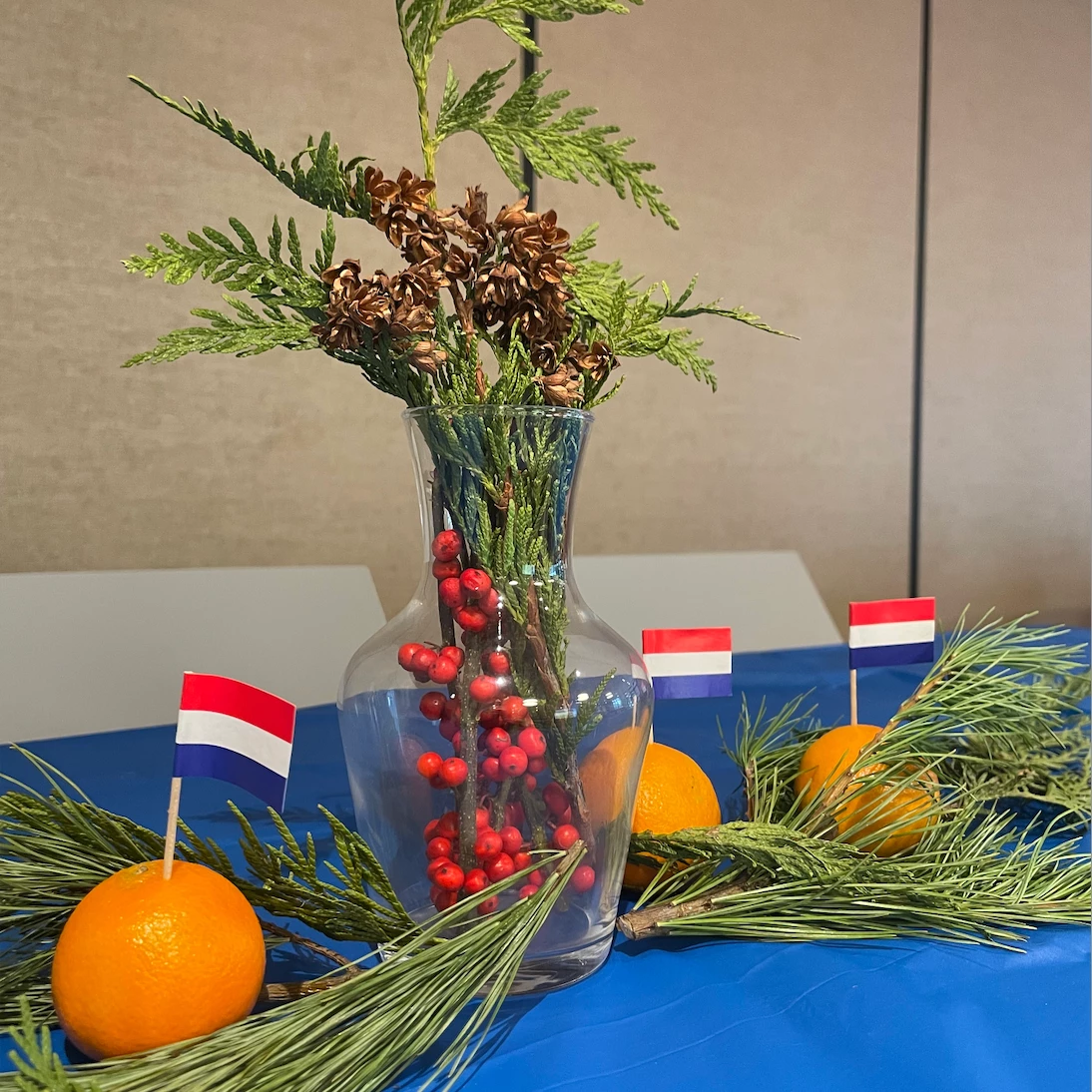 French flags stuck in some oranges around greenery in a vase on a table