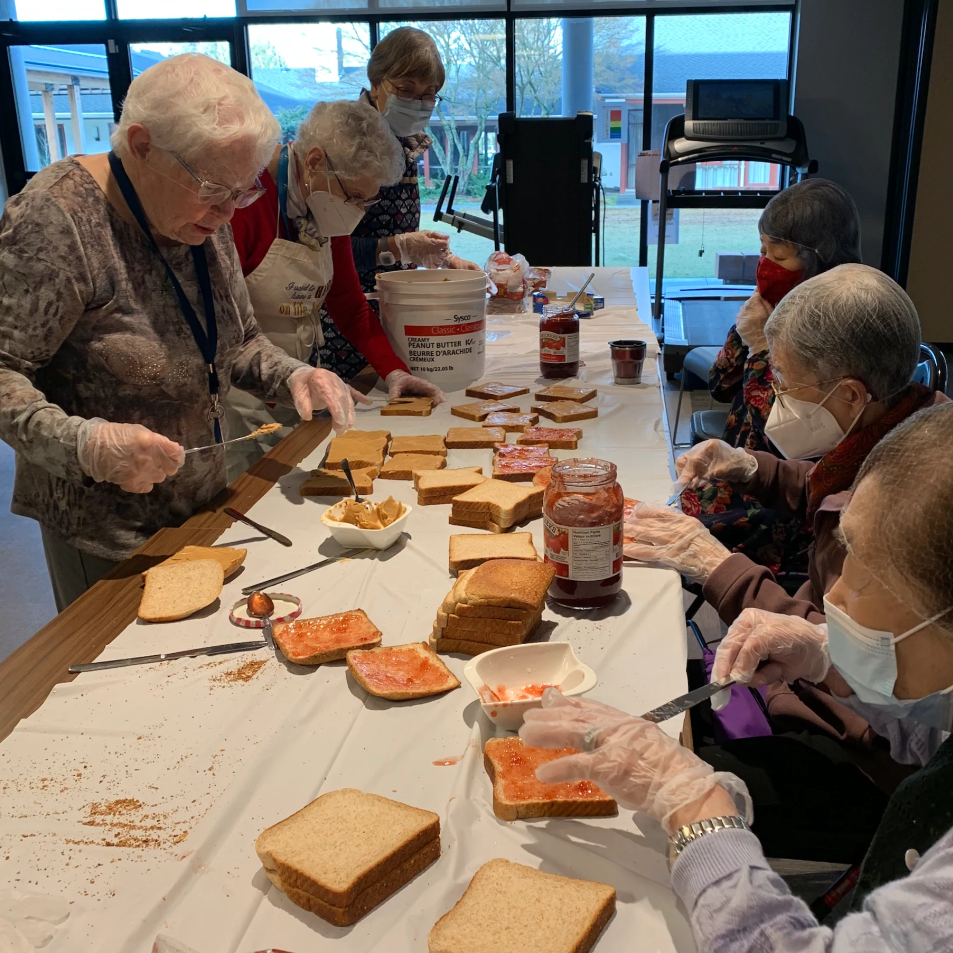 Seniors putting jam and peanut butter on slices of bread