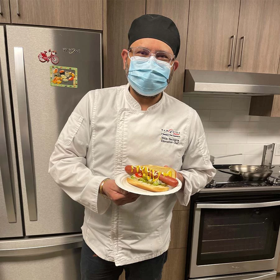 Chef holding a plate with a hotdog